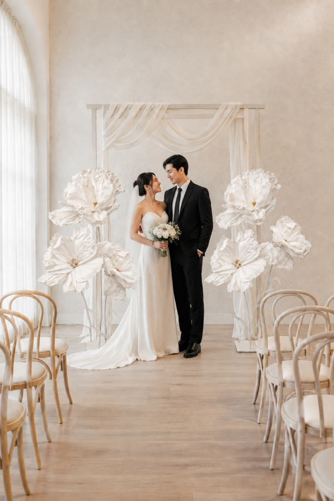 White giant paper flowers framing an indoor Melbourne wedding ceremony